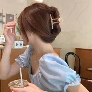 French style amber tortoiseshell acetate hair claw clip worn in a low bun hairstyle