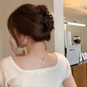 Elegant emerald green acetate hair claw clip styled on woman in a chic cafe setting