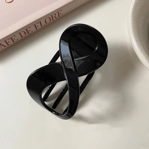 Detail of a sleek black infinity cross hair claw clip with a glossy resin finish