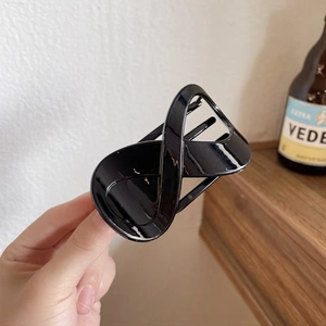 Detailed close-up of a glossy black criss-cross hair claw clip with smooth polished finish