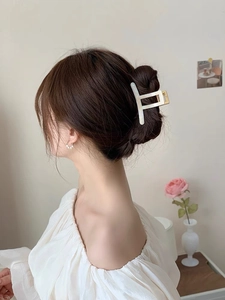 Macro view of cream white geometric hair claw clip styled on brunette hair with floral decor