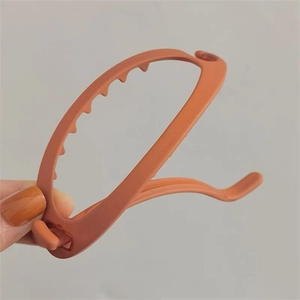Gros plan sur une pince banane orange mat avec un design incurvé et évidé pour chignons