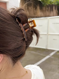 Close-up of tortoise shell pattern acetate hair claw clip with gold metal spring for women