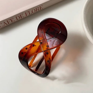 Detail of tortoiseshell patterned acetate hair claw clip with cross-twist design