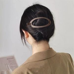 Pince à cheveux minimaliste marron mat pour chignons élégants présentée sur modèle