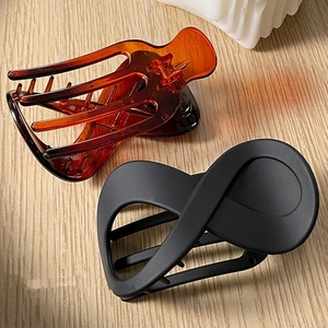 Set of 2 hair claws in matte black and amber tortoiseshell finish on wooden table