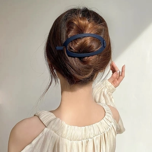 Détail d'une pince à cheveux ovale bleu marine mat pour chignon sous une lumière naturelle