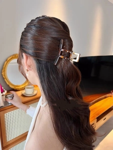 Macro shot of large amber acetate hair claw clip styled in French twist on brown hair