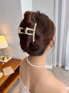 Detail of a marble textured acetic acid hair claw clip on model with elegant hollow square design