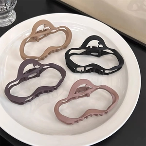 Détail de quatre pinces à cheveux mates en kaki noir violet et rose sur une assiette