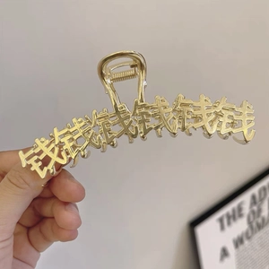 Dettaglio di una pinza per capelli in metallo dorato con ritagli di caratteri cinesi