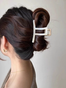 Detailed view of a white marble acetate shark hair claw clip worn on a high ponytail