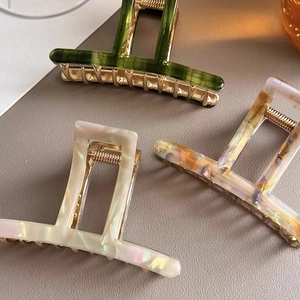 Three acetate hair claws in dark green, cream pink and amber marble textures