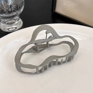 Détail d'une pince à cheveux mate grise aux vagues irrégulières sur une assiette blanche