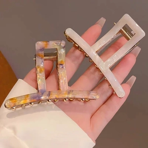Detail of a large marble texture acetate hair claw clip held in hand for size scaling