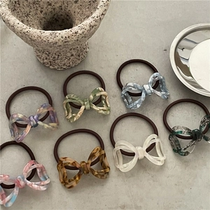 Close-up of seven acetate bow hair ties in assorted tortoiseshell and marble patterns