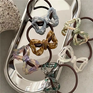 Set of six acetate marble butterfly hair ties in various colors on a silver tray