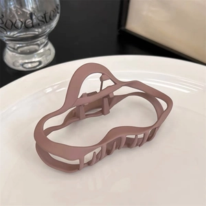 Vue macro détaillée d'une grande pince à cheveux rose mat au design ondulé et élégant