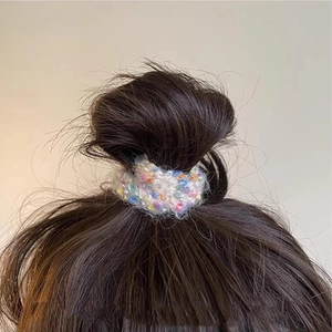 Detail of colorful knitted scrunchie with tweed texture worn on a brown hair bun