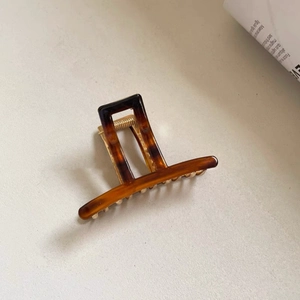 Macro view of tortoiseshell acetate claw clip with durable gold metal spring and teeth