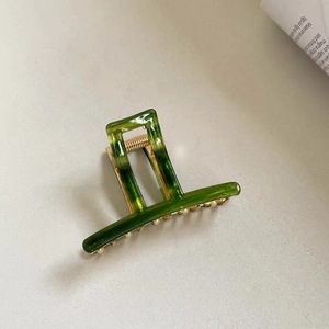 Close-up of green marble pattern acrylic hair claw clip with golden metal spring and teeth