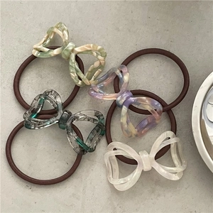 Detail of four marble texture acetate bow hair ties in ivory, green, purple and grey