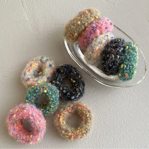 Close-up of colorful popcorn knit scrunchies with soft fuzzy texture in a glass dish