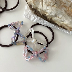 Detailed close-up of three acetate bow hair ties in pearlescent and marble textures