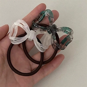 Detail showing two high-elastic hair ties with marbled resin bow charms in white and green