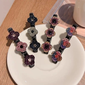 Détail de quatre barrettes à fleurs ornées de cristaux colorés sur une table en bois