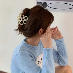 Dettaglio di una molletta per capelli a fiore color crema indossata da una modella