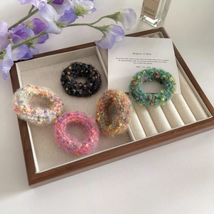 Set of five colorful tweed knit hair ties in assorted colors on a rustic wooden tray