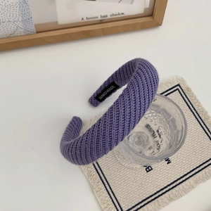 Gros plan du bandeau tricoté violet montrant la texture de laine et l'étiquette faite main