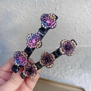 Détail de deux pinces à cheveux noires avec motifs de fleurs en strass colorés