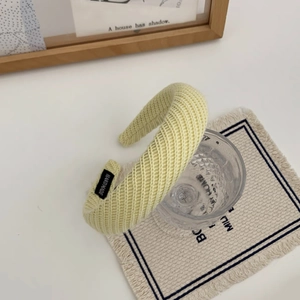 Détail d'un serre-tête en tricot jaune crème avec étiquette fait main et texture