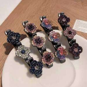 Détail de quatre pinces à cheveux fleurs ornées de strass brillants dans un plat en céramique