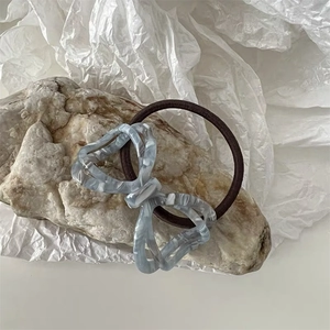 Macro shot of acetic acid butterfly knot hair tie with grey marble texture and elastic band