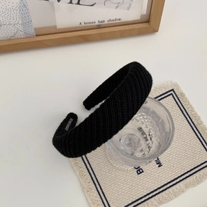 Détail d'un bandeau en tricot noir avec étiquette 'HANDMADE' et texture en grosse maille