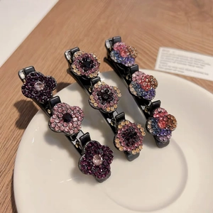 Gros plan de trois barrettes à fleurs en strass étincelants sur une assiette en céramique