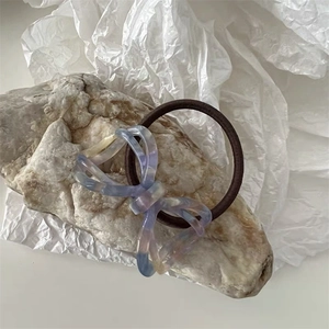 Detail of elegant acetate bow hair tie with marble texture on natural stone and paper