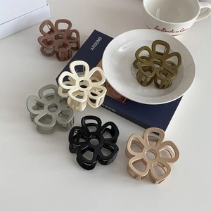 Pinze per capelli a fiori in vari colori Morandi su una scrivania bianca minimalista