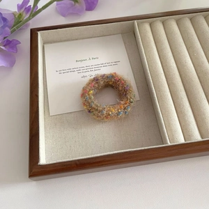 Detailed texture of a tweed knit hair scrunchie with colorful fibers on a jewelry tray