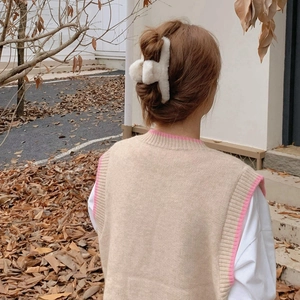 Detail of white plush hair claw clip showing soft faux fur texture on knit sweater