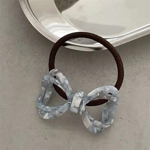 Macro detail of high-elastic hair rope with blue marble texture acetate bow pendant