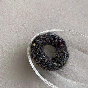 Detailed macro shot of the colorful knitted texture on this black elastic hair scrunchie