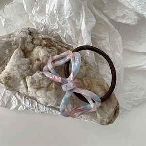 Detail of acetate marble pattern bow hair tie on rustic stone and art paper