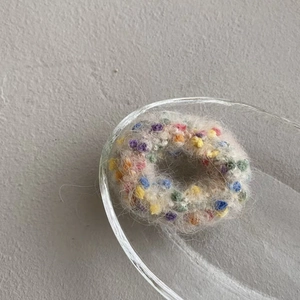 Close-up of a colorful knit hair tie in a glass bowl with soft plush texture details