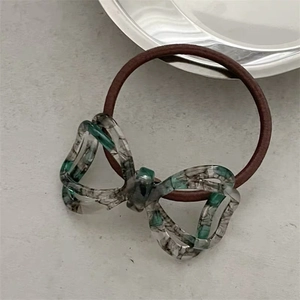 Detailed macro view of the marble texture acetate bow on a brown elastic hair tie