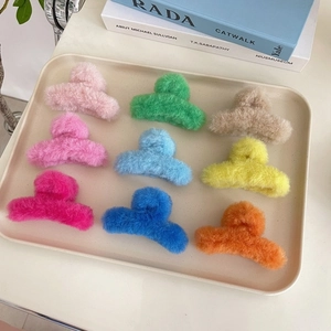Set aus neun Plüsch-Haarklammern in verschiedenen Farben auf einem cremefarbenen Tablett