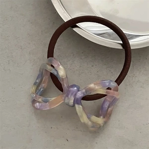 Macro detail of acetate bow hair tie with marble texture on grey stone surface